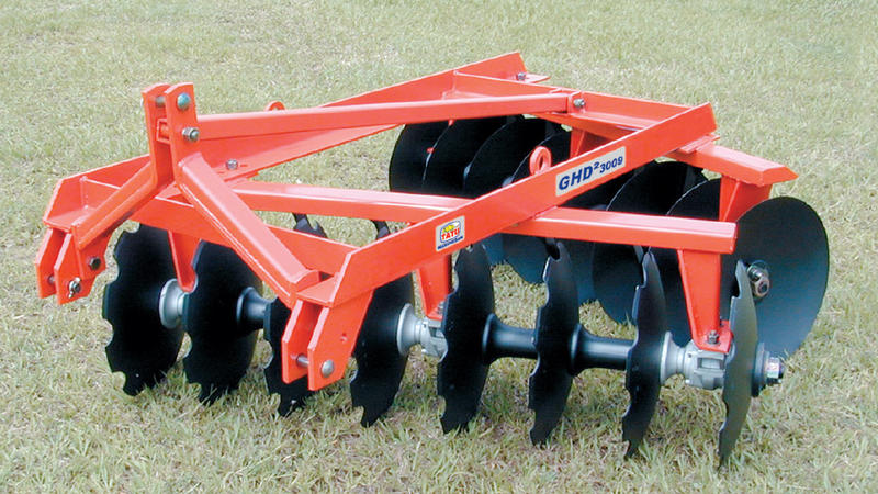 An orange Tatu GHD-2-3009A plow attachment on a grass field.